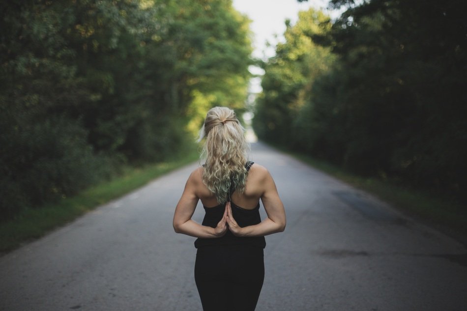 blonde girl in yoga pose on the road among nature