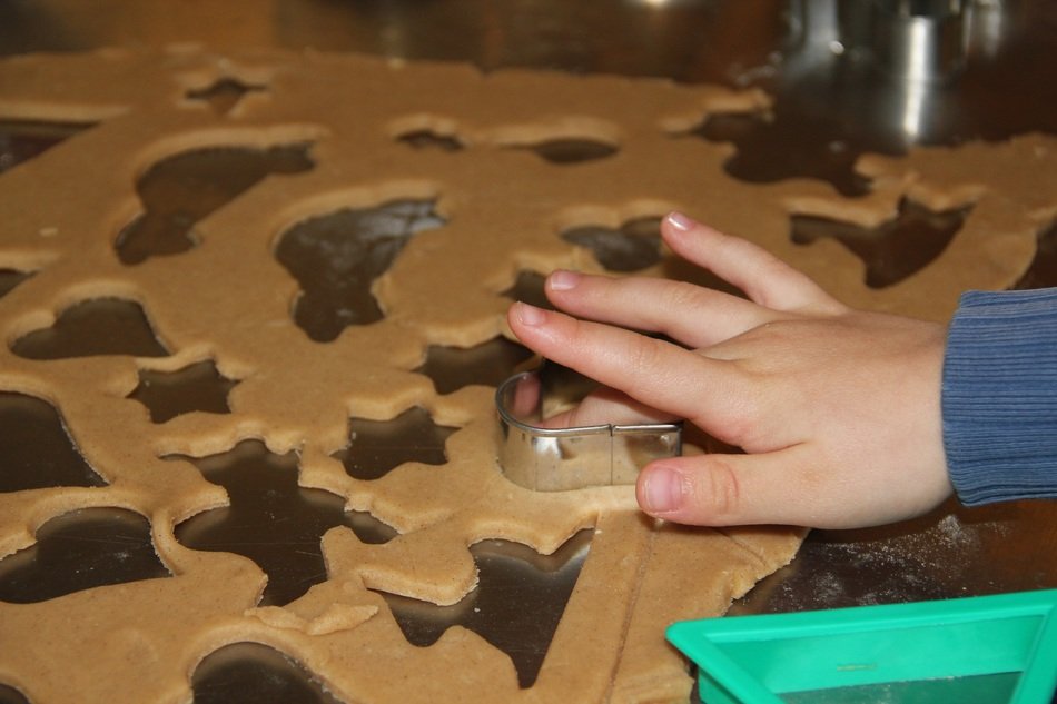 child cuts cookies out of dough