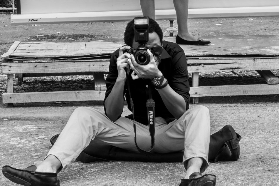 Man with camera sits on ground