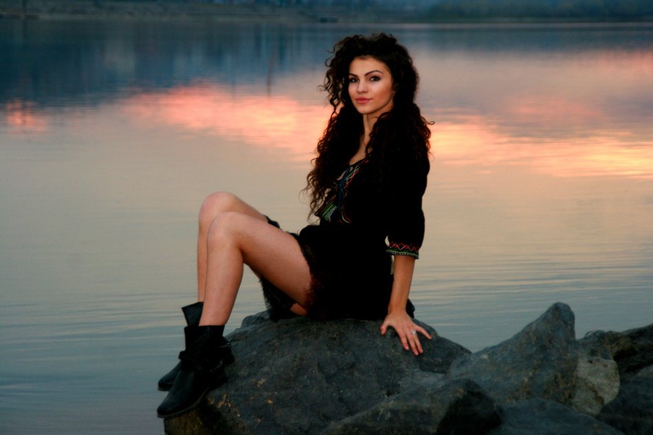 beautiful girl in a black dress near the lake at dusk