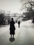 Black and white image of people on the road among the plants