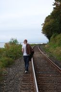 young man with a leather jacket walks on a rail