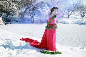 young Girl in long red Dress posing on snow at pond