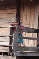 little asian child near a wooden hut