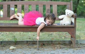 little girl lying on a bench in the park