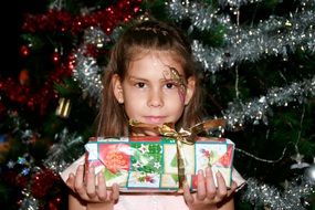 little girl with a gift near a shiny Christmas tree