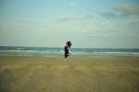 happy young girl dancing on beach at sea