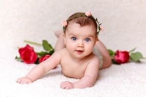 cute baby with blue eyes among the roses