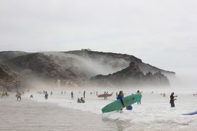 surfers on the beach by the ocean in Praia do Amado