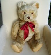 teddy bear with a red bow in a chair