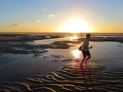 boy runs along the beach after low tide