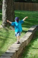 Child boy balancing on Stone fence