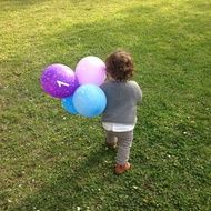 little child with colorful balloons on the lawn