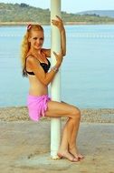 beautiful blonde in a bikini on a pylon near the water