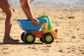 child plays with toy truck in the sand