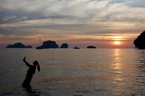 girl makes a selfie in the sea at beautiful sunset background