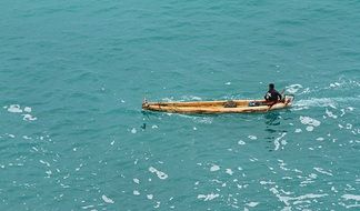dark skin man in wooden fishing boat on sea