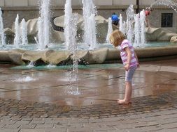 little girl playing in fountain