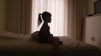 little girl is sitting on the bed
