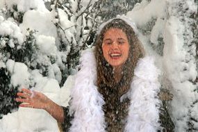 young Girl in feather boa in front of forest on Snowy weather