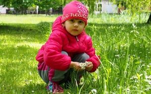 little girl squatting on green grass