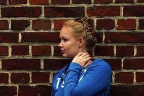 girl stands near a brick wall