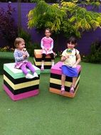 children sit on colorful cubes in the yard