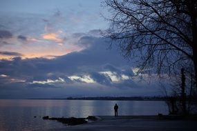 man stands on the shore of Lake Geneva against the evening sky in Switzerland