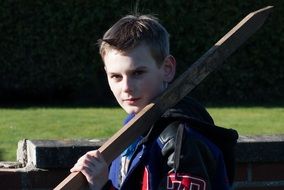 guy holds a stick on his shoulder