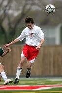 soccer player in white-red uniform with a ball
