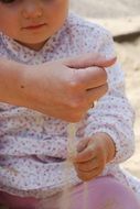 female hand sprinkling sand in front of child
