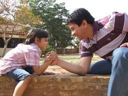 cheerful Child boy and man holding hands, arm wrestling