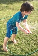 Child Playing with Water on the green grass