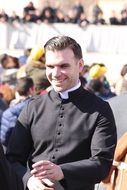 young smiling priest among people
