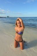 girl in bikini kneeling on the beach in mexico
