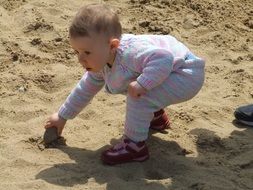 little child plays in the sandbox