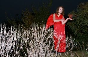 pretty Girl in Winged Red dress with Heart on hand at night