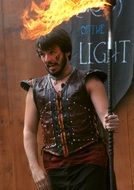 a man in a leather vest and a burning torch in his hands