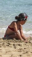girl playing on the beach with sand