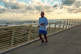 man runs on a footpath near the sea