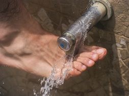 Manâs Foot beneath Water tap, washing up