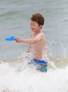 boy playing with toy shark in the sea