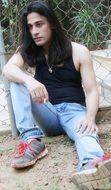 A man with long hair posing while sitting on the ground