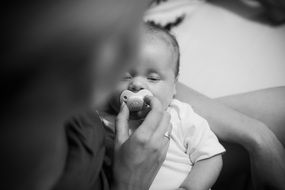 newborn with pacifier in black and white image