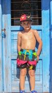 Child Boy in bright pants stands at Blue Door