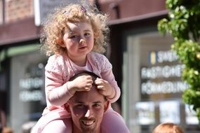 a little girl is sitting on the shoulders of a man