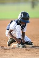 baseball player is tying shoelaces on the field