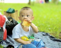 Asian child is eating pita bread in the park