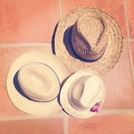 Family of three Summer Straw hats on tile floor