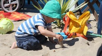 Child boy in colorful clothing Plays with Sand on Beach